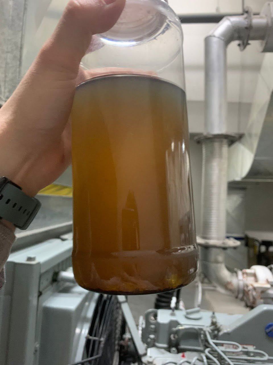 Muestra de diesel turbio con sedimento y lodo en el fondo, tomada de una planta